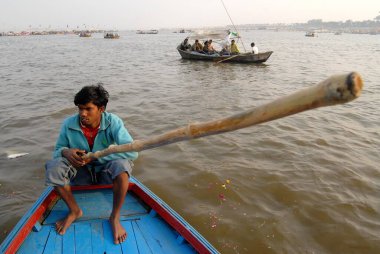 Denizci, elinde uzun bambuyla Ganj, Yamuna ve Saraswati nehirleri, Allahabad, Uttar Pradesh, Hindistan 'ın kesiştiği noktadaki feribotuna binmiş. 