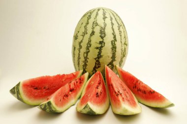 Fruits ; One full watermelon with light and dark green stripes with five cut slices showing watery red pulp and black seeds ; Pune ; Maharashtra ; India clipart