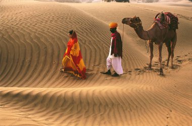 Çöl yürüyüşçüleri Rajasthani erkek ve kadın deve ile yürüyorlar, Rajasthan, Hindistan 