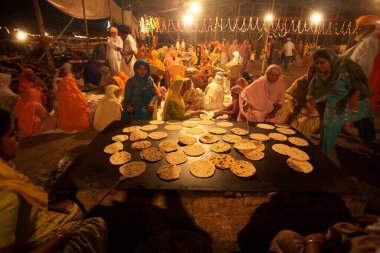 Sikh women devotees making rotis inside community kitchen in Sachkhand Saheb Gurudwara, 300th year of Consecration of  Guru-Granth Sahib in Nanded, Maharashtra, India 30-October-2008  clipart