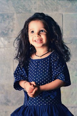 Evde poz veren mavi elbiseli şirin bir Hintli kız portresi.