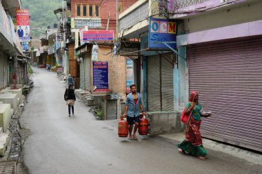 Dar sokakta LPG silindiri taşıyan bir adam Banjar kasabası, Tirthan Vadisi, Kullu, Himachal Pradesh, Hindistan, Asya 