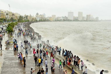 İnsanlar Marine Drive, Mumbai, Maharashtra, Hindistan ve Asya 'da muson deniz dalgalarının tadını çıkarıyorlar.