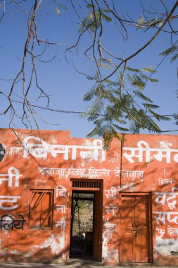 Reklamlı turuncu duvar; Dilwara köyü; Udaipur; Rajasthan; Hindistan