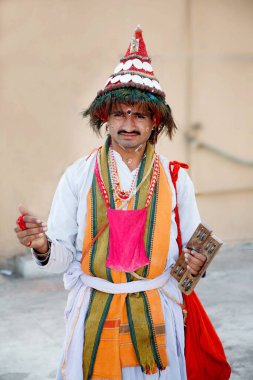 Vasudev in headgear of peacock feather holding chiplya or kartals  clipart