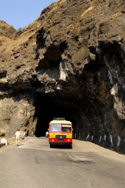 Tunnel constructed by cutting very hard black rock of Sahyadri mountain and state transport bus at Malshej Ghat ; District Thane ; Maharashtra ; India clipart