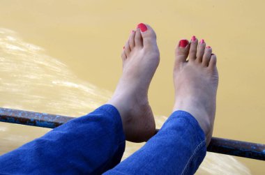 female feet hanging over River Godavari Rajahmundry Andhra Pradesh India clipart