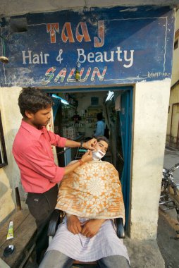 Genç bir adam Taj saç ve güzellik salonunda sakalını kestiriyor; Dehradun; Uttaranchal; Hindistan