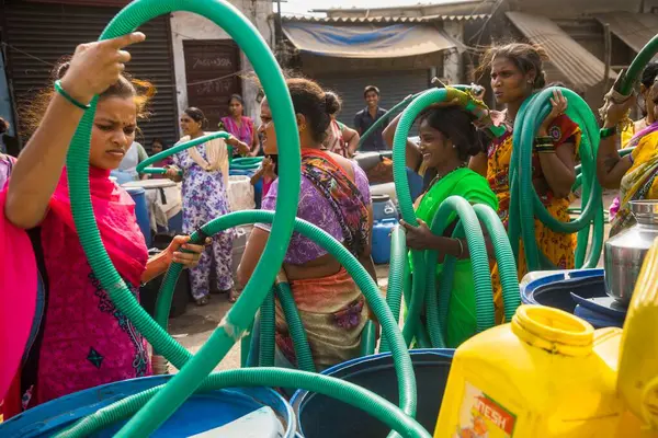 İnsanlar su tankerinden, Bhiwandi 'den, Maharashtra' dan, Hindistan 'dan plastik varillere su dolduruyorlar. 