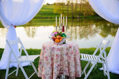 Göldeki bir parkta, mumlar ve çelenklerle süslenmiş güzel bir çadırda buluşma ya da evlenme teklifi için romantik bir yer. Meyveli bir masa ve bir şişe şarap..