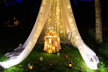 Göldeki bir parkta, mumlar ve çelenklerle süslenmiş güzel bir çadırda buluşma ya da evlenme teklifi için romantik bir yer. Meyveli bir masa ve bir şişe şarap..