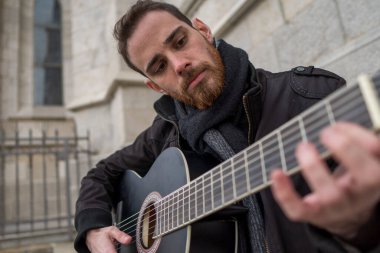 Sakallı adam sokakta gitar çalmayı öğreniyor. Hobi konsepti.