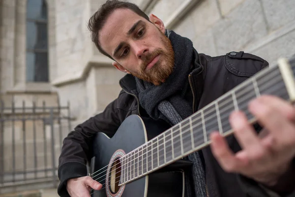 Sakallı adam sokakta gitar çalmayı öğreniyor. Hobi konsepti.