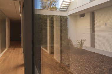 Parke zemin, beyaz duvarlar ve güzel bir iç bahçesi olan lüks bir evin koridoru..