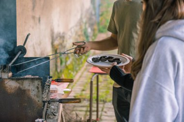 Tanımlanamayan genç adam ve kadın kırsalda barbekü hazırlığı yapıyorlar..