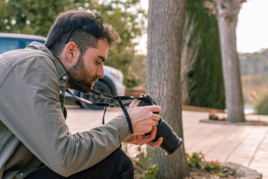 Güneş gözlüklü ve kulağına piercing takmış bir fotoğrafçı refleks kamerasındaki fotoğraflara bakıyor...