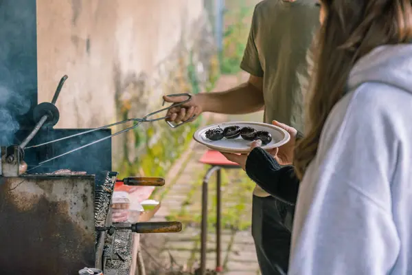 Tanımlanamayan genç adam ve kadın kırsalda barbekü hazırlığı yapıyorlar..