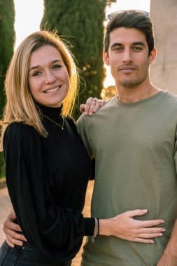 Kameraya bakıp gülümseyen genç ve çekici bir çiftin portresi. Dikey.