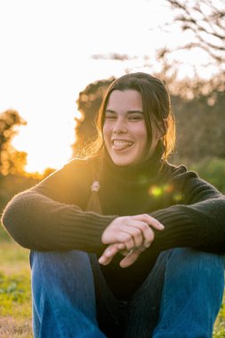 Kotlu ve siyah kazaklı genç bir kızın göz açıp kapayıncaya kadar dilini çıkardığı yakın plan..