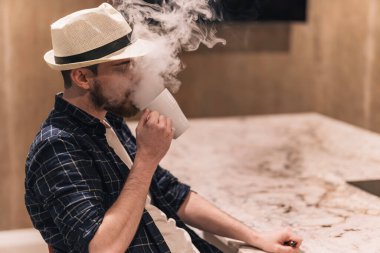 Sigarayı bırakma kavramı. Adam yoğun dumanla bir fincan içiyor. Boşluğu kopyala.