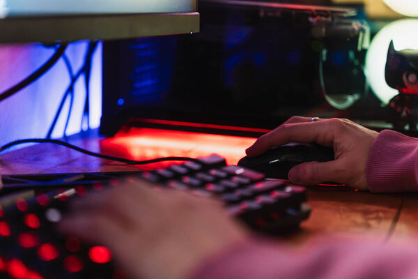 Hands of a gamer playing videogames with his LED keyboard and mouse in his gaming setup.