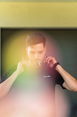 Genç siyah saçlı adam ağzında puroyla müzik dinliyor..