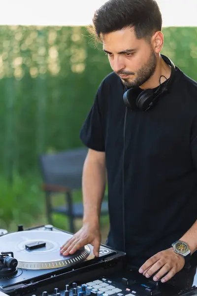 stock image DJ in black clothes testing songs for his next album.