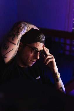 Şapkalı genç adam çalışma alanındaki bir fotoğrafı nasıl düzenleyeceğini düşünüyordu..