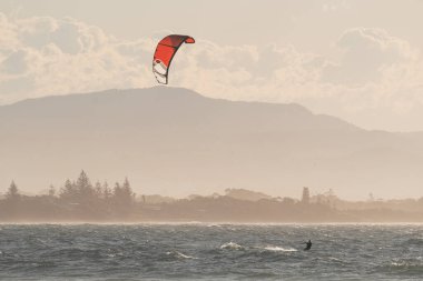 Sunset 'te Byron Bay plajında uçurtma uçuran son sınıf öğrencisi. Avusturalya.