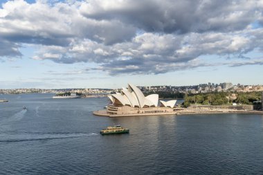 Öğleden sonra Sydney Opera Binası 'nın hava manzarası bulutlu bir gökyüzü ile yelken açan tekneleriyle.