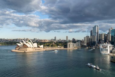 Bulutlu bir günde denizde yüzen teknelerle Sydney Opera Binası 'nın geniş açılı görüntüsü..