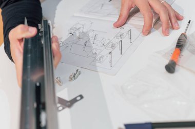 Kadınların elleri mobilya montajı talimatlarına uyar.. 