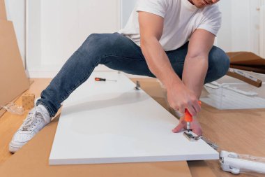 Yeni bir apartmanın parke zemininde mobilya montajı yapan profesyonel bir marangoz..