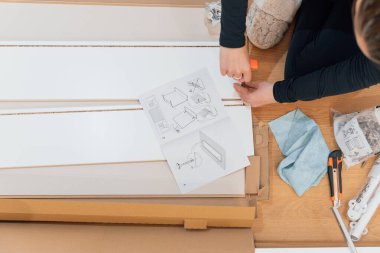 Genç bir kadın yeni apartmanının zemininde mobilya montajı yapıyor.. 