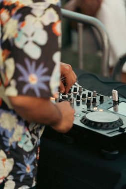 Hawaii gömlekli bir DJ gece bir partide mikser konsolunda çalıyor. Dikey