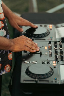 Açık hava partisinde mikseriyle müzik çalan bir DJ 'in elleri. Dikey