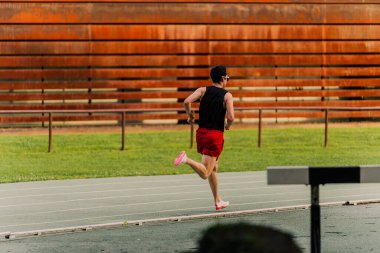 Genç adam antrenmandan önce atletizm pistinde ısınıyor.. 