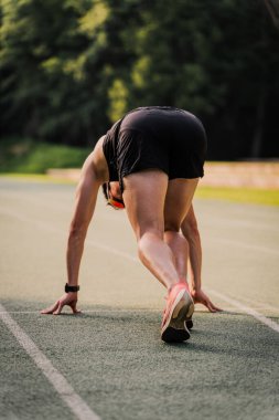 Atletizm pistindeki antrenman sırasında başlangıç pozisyonunda olan profesyonel atlet.