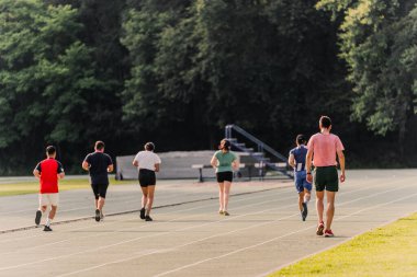Bir grup amatör koşucu atletizm pistinde antrenman yapıyor..