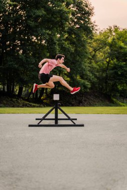Engelli koşusunda atlama sırasında havada bir atlet. Dikey.