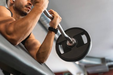 Spor salonunda kollarını Olimpik halterle çalıştıran Latin bir adam..