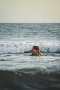 Dişi sörfçü okyanusta sörf tahtasının üzerine uzandı..