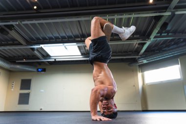 Atletik vücutlu genç bir adam içeride break dans yapıyor..