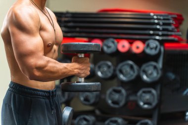 Spor salonunda dambılları kaldıran tanınmamış bir adamın üst vücudu..