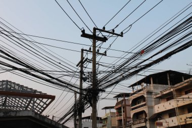Phitsanulok, Tayland, 11 Nisan 2015: Phitsanulok şehrindeki elektrik direklerinin arasında birçok elektrik kablosu gergin, mavi gökyüzü