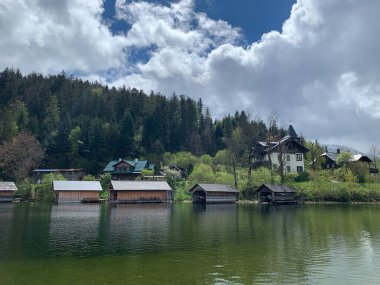 Altaussee, Austria, April 20, 2024: Traditional wooden boathouses at lake Altaussee in the Austrian Alps. Cloudy spring day. Beautyful residences and villas at lakeside.  clipart