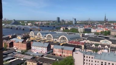 Riga, Letonya, 3 Mayıs 2024: Letonya Bilim Akademisi 'nden Eski Şehir ve Riga Merkez Pazarı' na üst görünüm. Baharda güneşli bir günde Letonya 'nın Riga kentinin genel manzarası. Tren ve trafik köprülerden geçiyor.