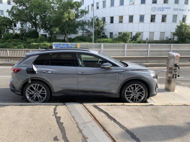 Viyana, Avusturya, 2 Haziran 2024: Spittelau 'daki Viyana Üniversitesi binası önünde Wien Energie tarafından yüklenen gri Audi Q4 e-tron. Kablo dışarıya yönlendirildi.