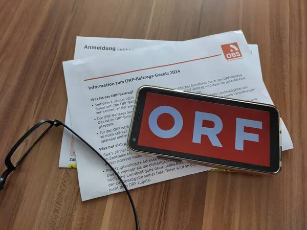 Viyana, Avusturya-23 Haziran 2024: Akıllı telefon ekranında Avusturya Yayın Kurumu (Oesterreichischer Rundunkt, ORF) logosu, masadaki gözlükler ve yeni yayın vergisi ödeme yasası hakkında bilgi. Avusturya 'nın TV lisans ücreti.