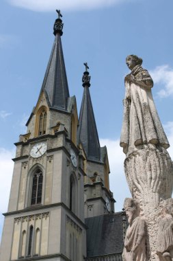 Admont, Styria, Austria, July 13, 2024: View of the 67m tall staples of Admont Abbey Church with statue of female founder Saint Hemma of Gurk. Benedictine Monastery.  Neo-Gothic style. Vertical image, blue sky. clipart